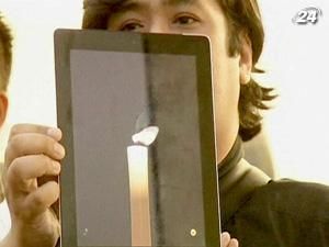 Люди несут цветы, свечи и яблоки в магазины Apple Люди несут цветы, свечи и яблоки в магазины Apple