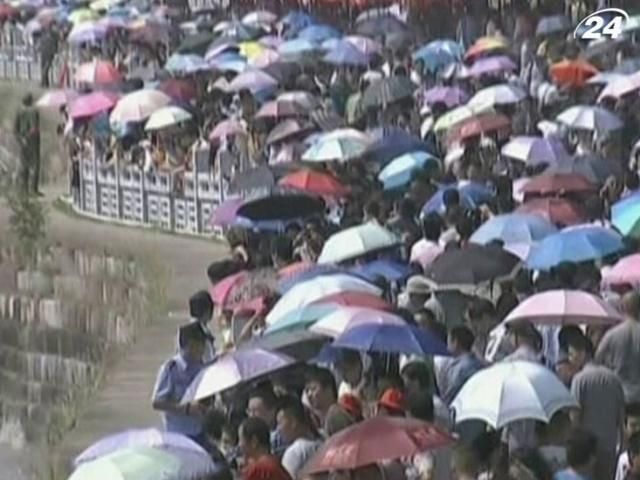 Тысячи китайцев под зонтиками собрались на берегу реки
