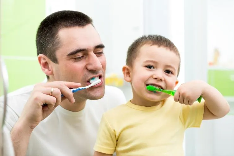 Дитина чистить зуби з татом
