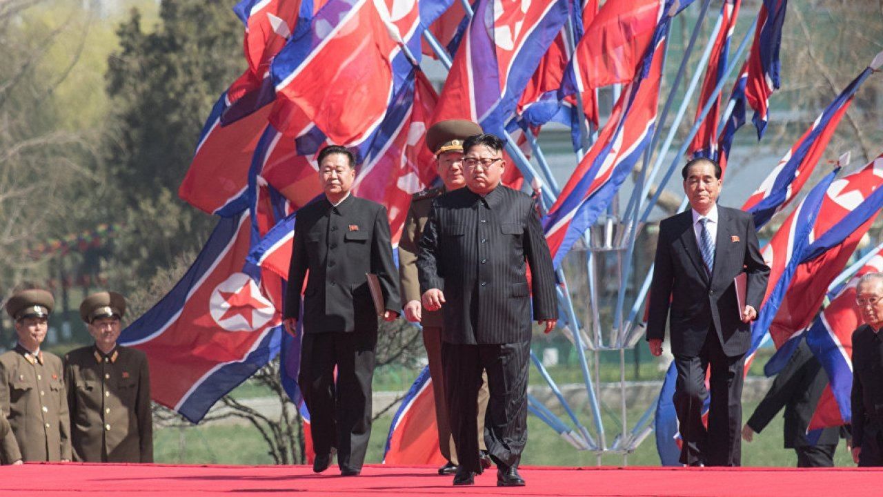 Кім Чен Ин на фоні прапорів КНДР