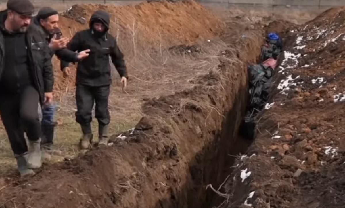 В Мариуполе коммунальщики хоронят погибших в братской могиле: видео преступлений России - 24 Канал