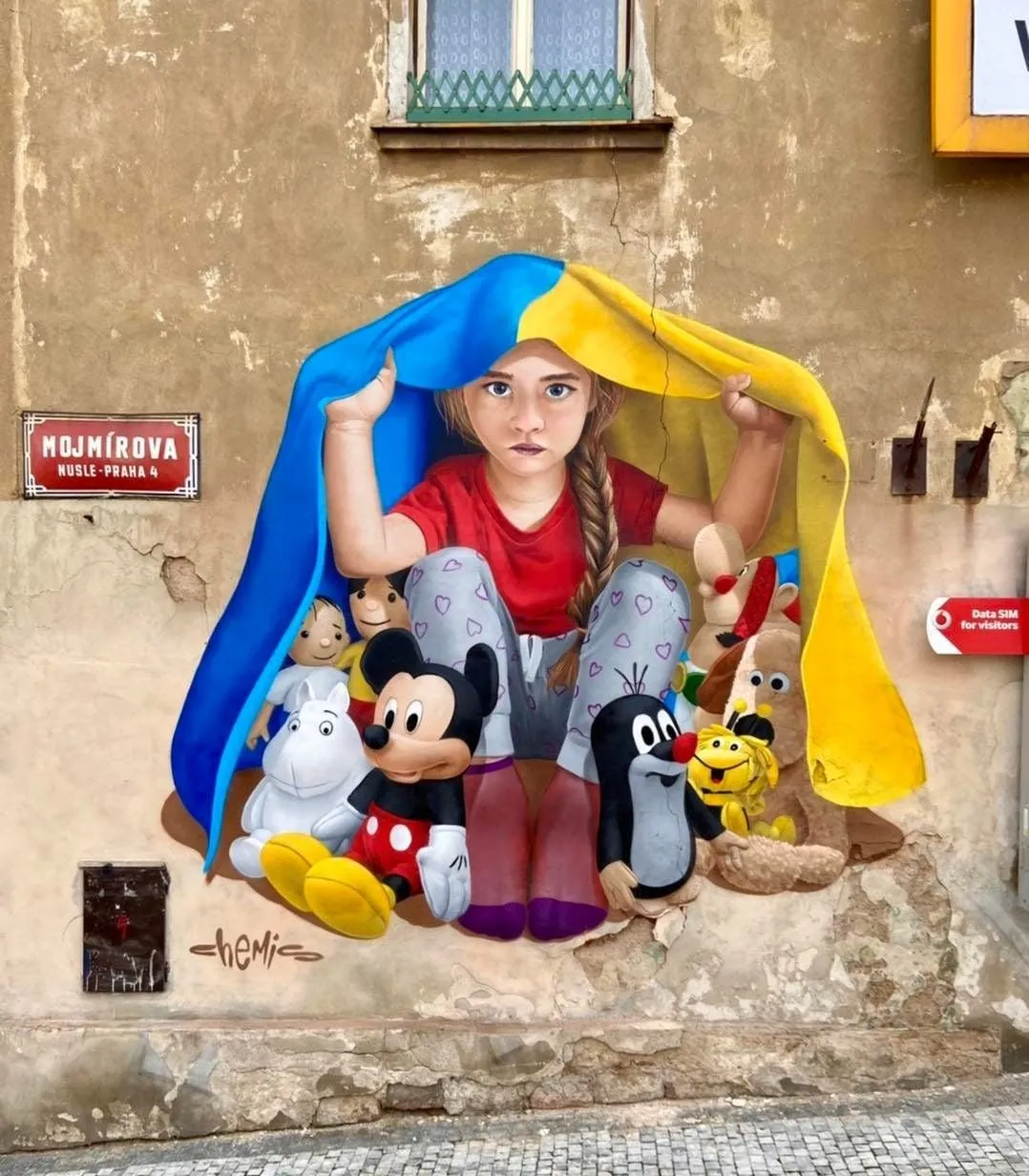 На будинку в Празі з'явився мурал з маленькою українкою, яка захищає казкових персонажів На будинку в Празі з'явився мурал з маленькою українкою, яка захищає казкових персонажів