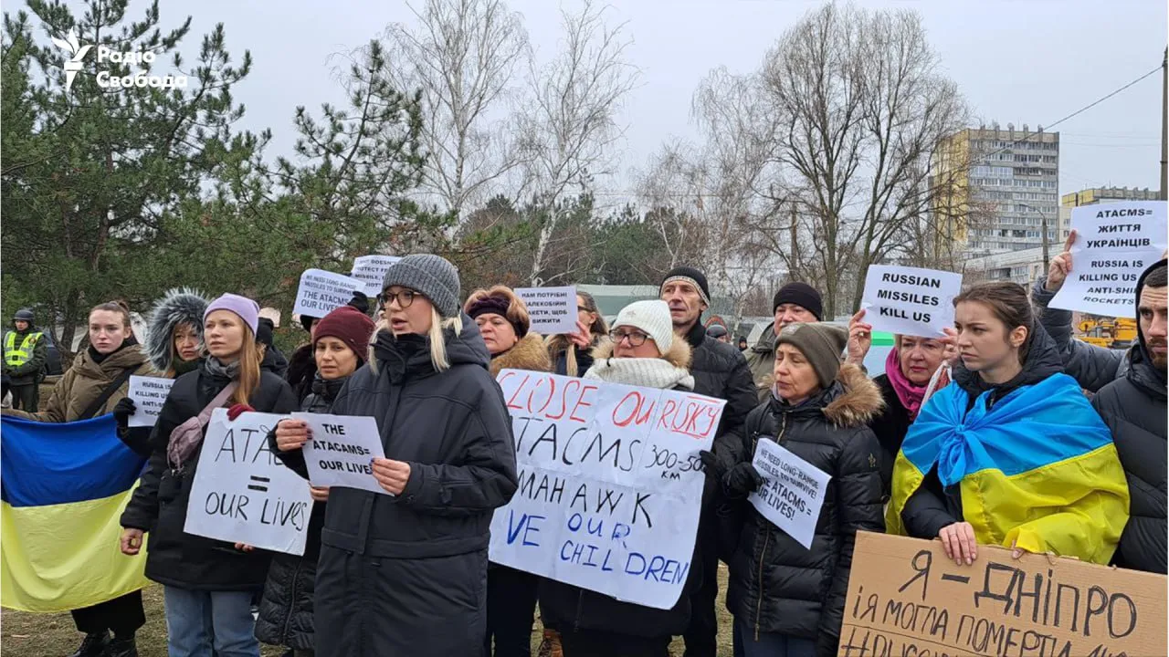 Українці з плакатами зібралися біля зруйнованого будинку у Дніпрі