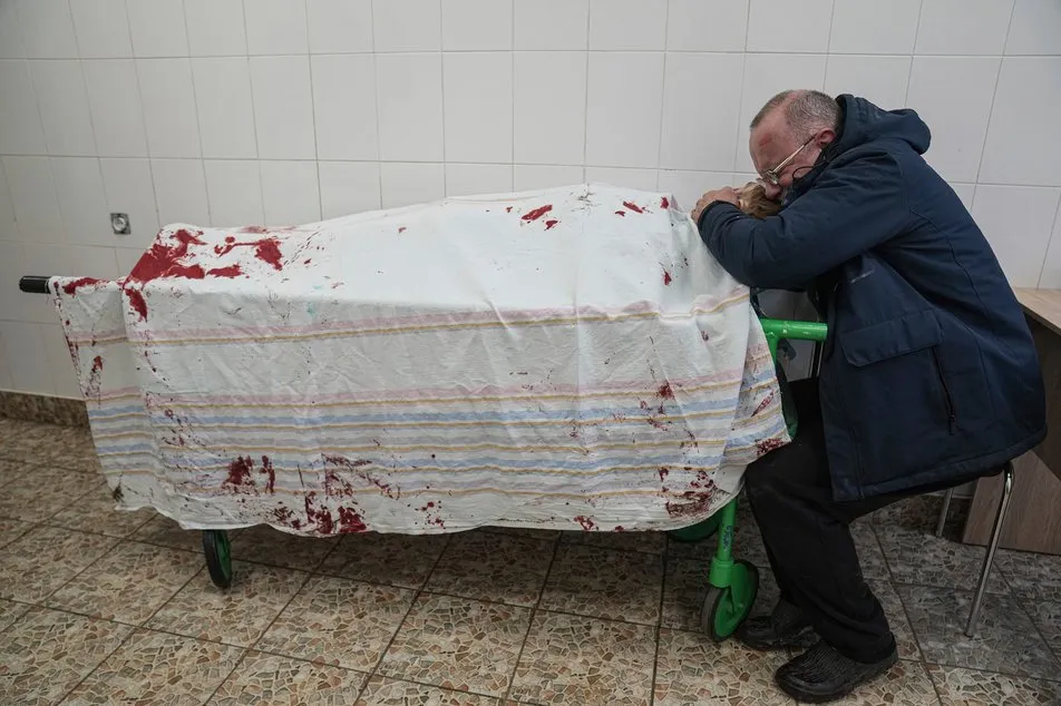 Отец плачет над убитым сыном в результате обстрела Мариуполя