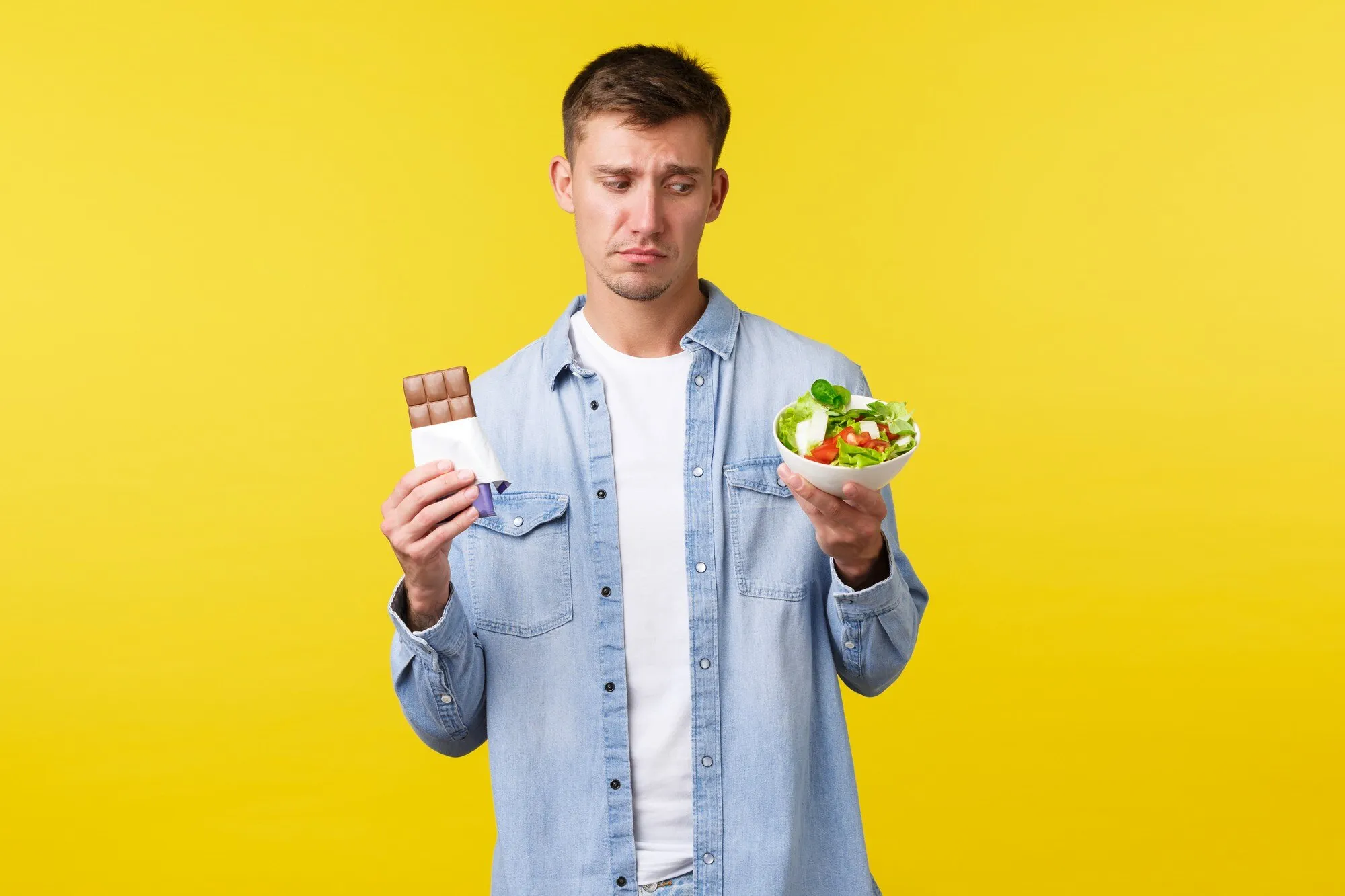 Мужчина на диете выбирает между шоколадом и салатом