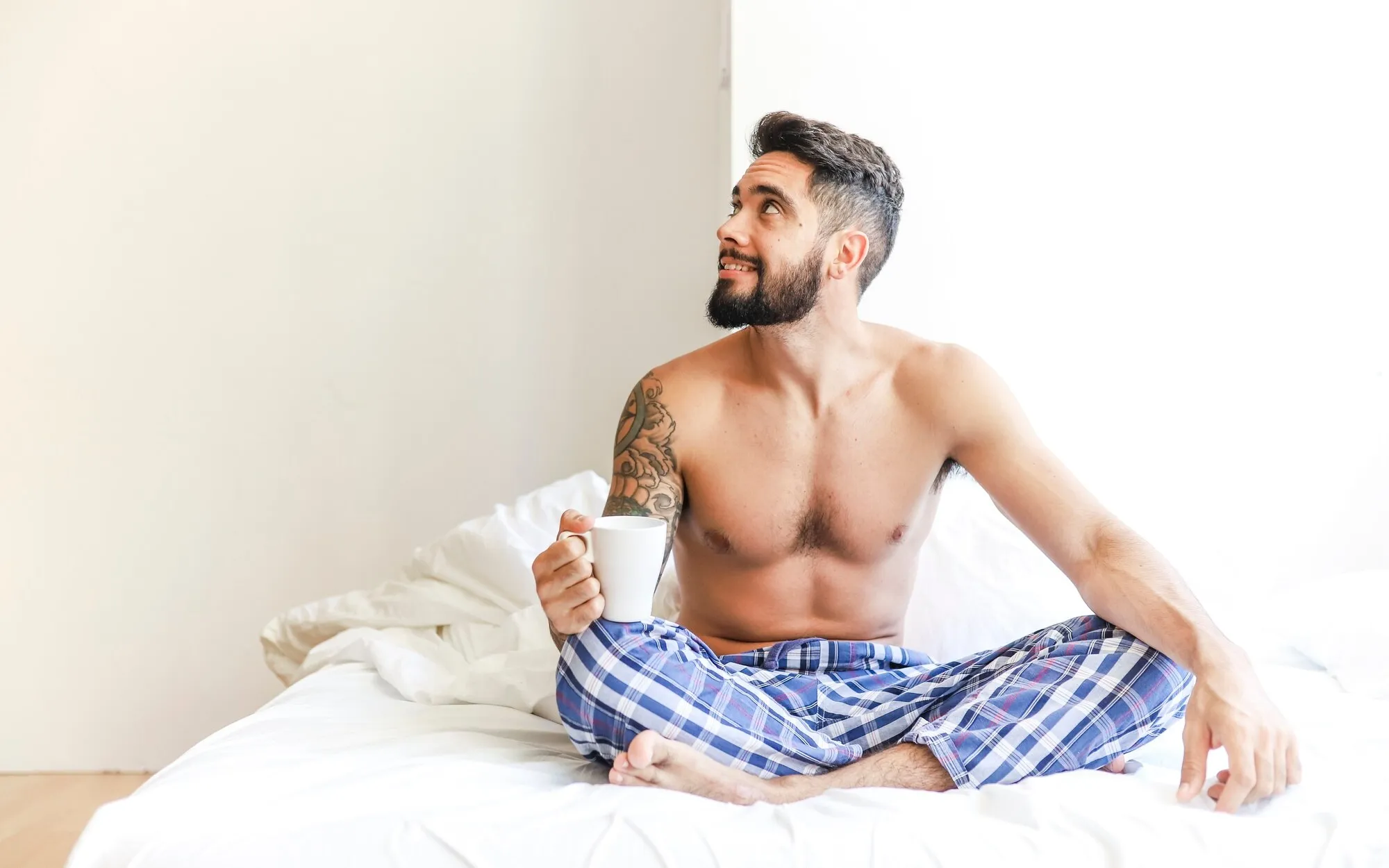Мужчина утром пьет кофе в постели