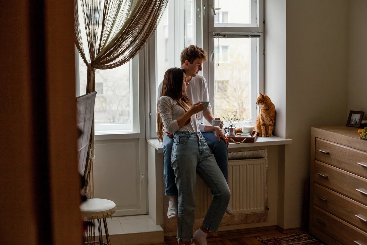 Пара пьет кофе дома и смотрит на кота