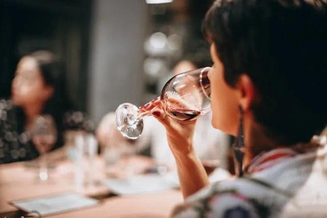 Женщина пьет вино из бокала
