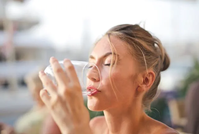 Жінка п'є воду з стакана