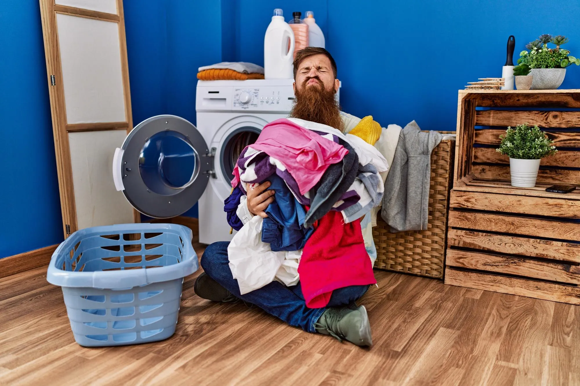 Мужчина несет одежду к стиральной машине