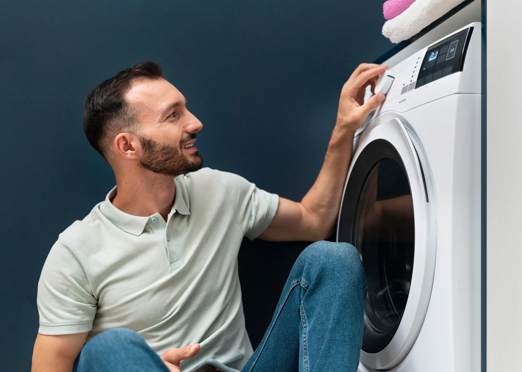 Мужчина выбирает режим стирки стиральной машины