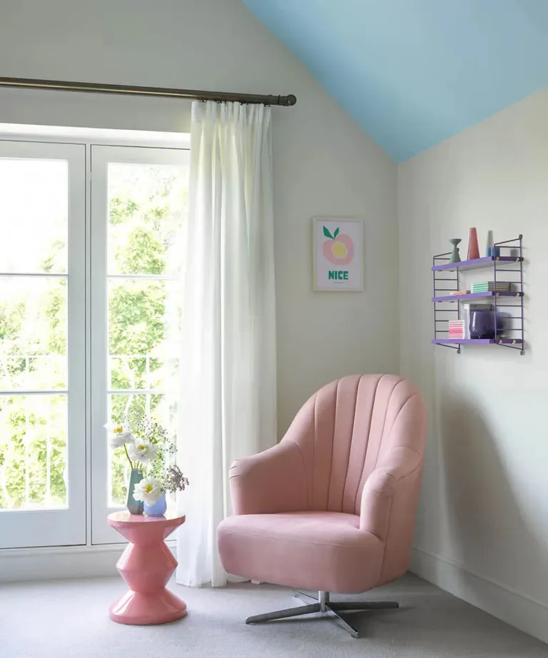 Нейтральная спальня с голубым потолком и розовым креслом