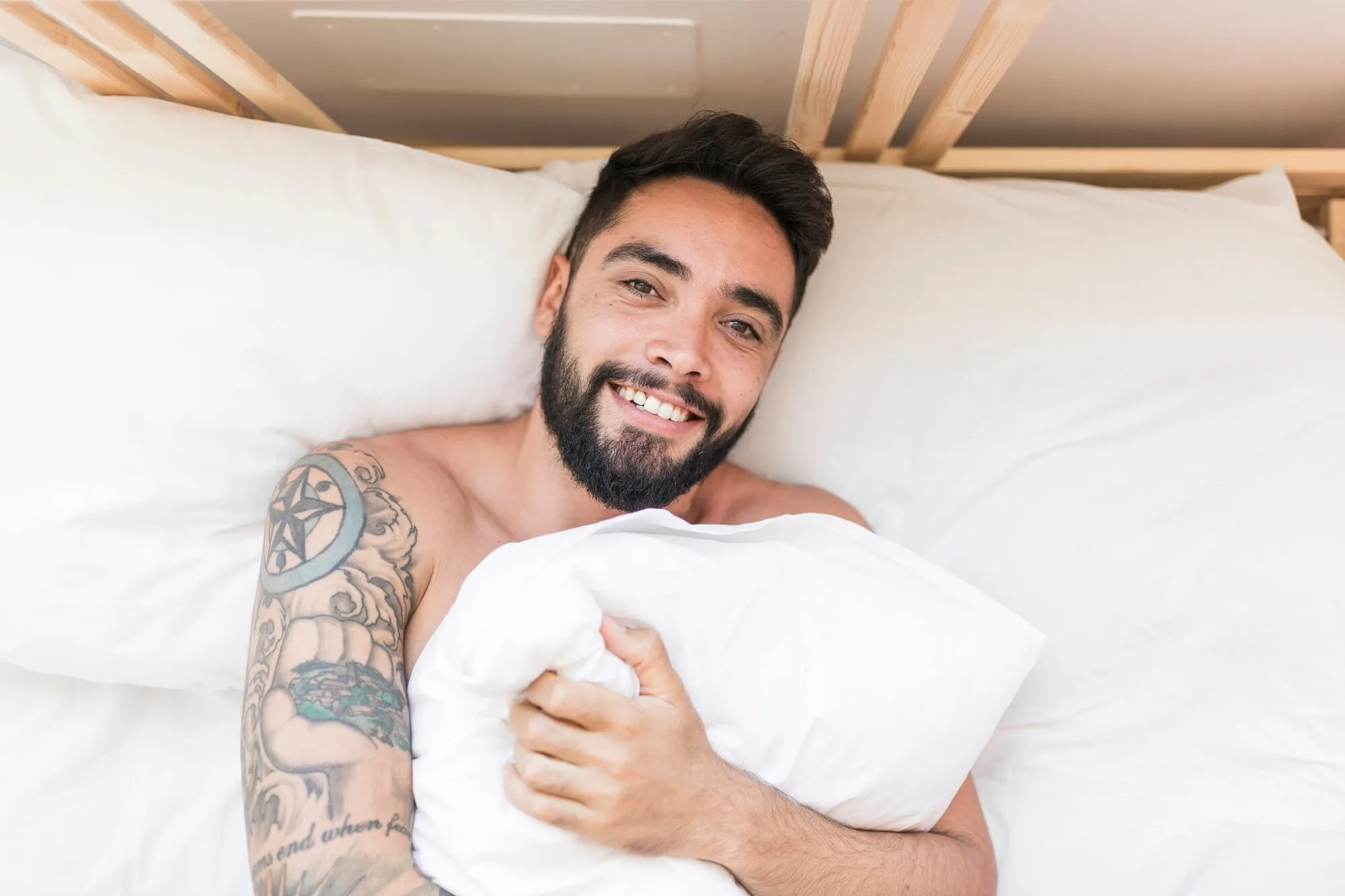 Мужчина на кровати обнимает подушку