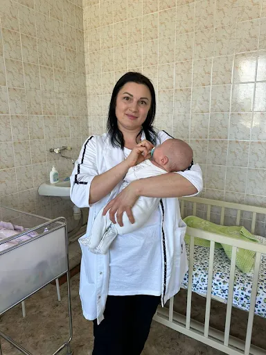 Алла Мельничук держит новорожденного ребенка