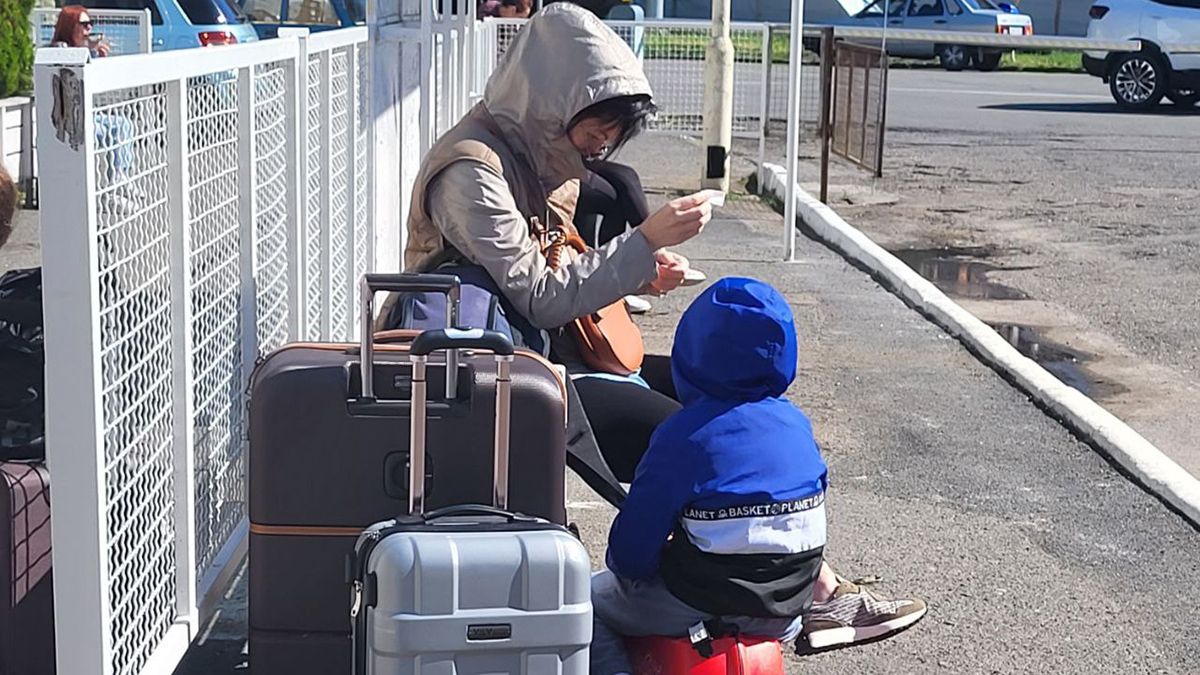 Жінка з дитиною сидять біля валізи Жінка з дитиною сидять біля валізи