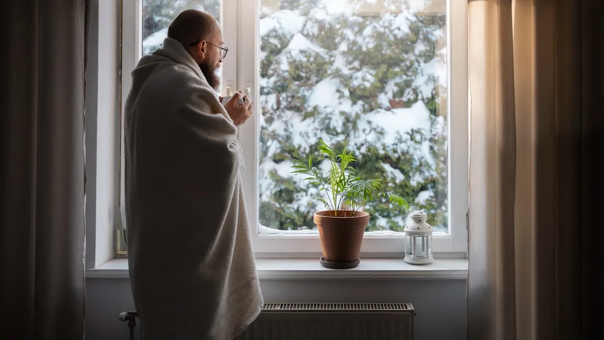мужчина смотрит в окно на зимний пейзаж мужчина смотрит в окно на зимний пейзаж