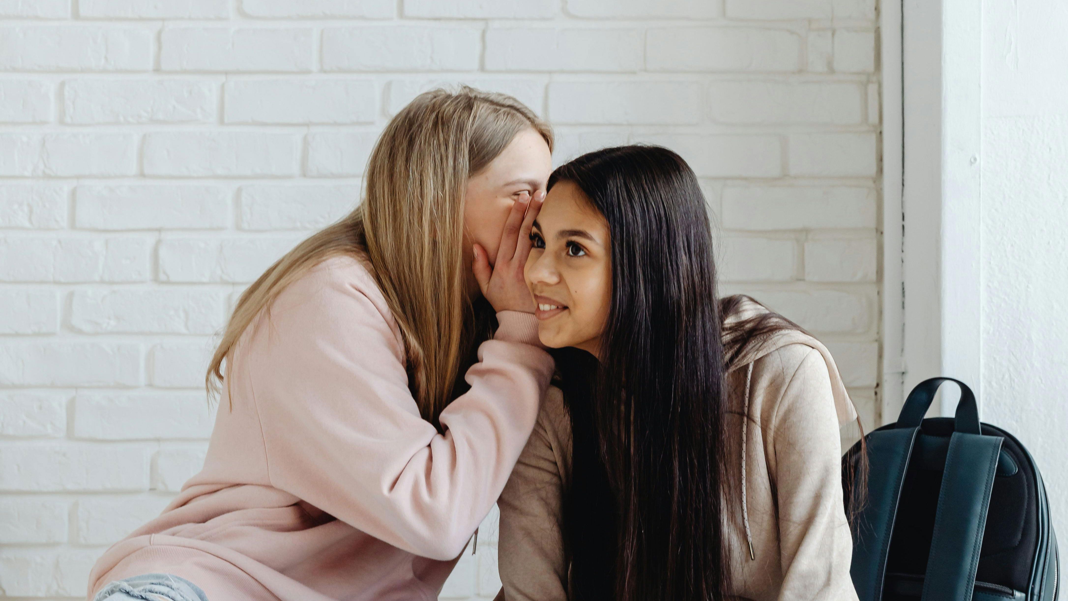 Дівчина шепоче на вухо подрузі Дівчина шепоче на вухо подрузі