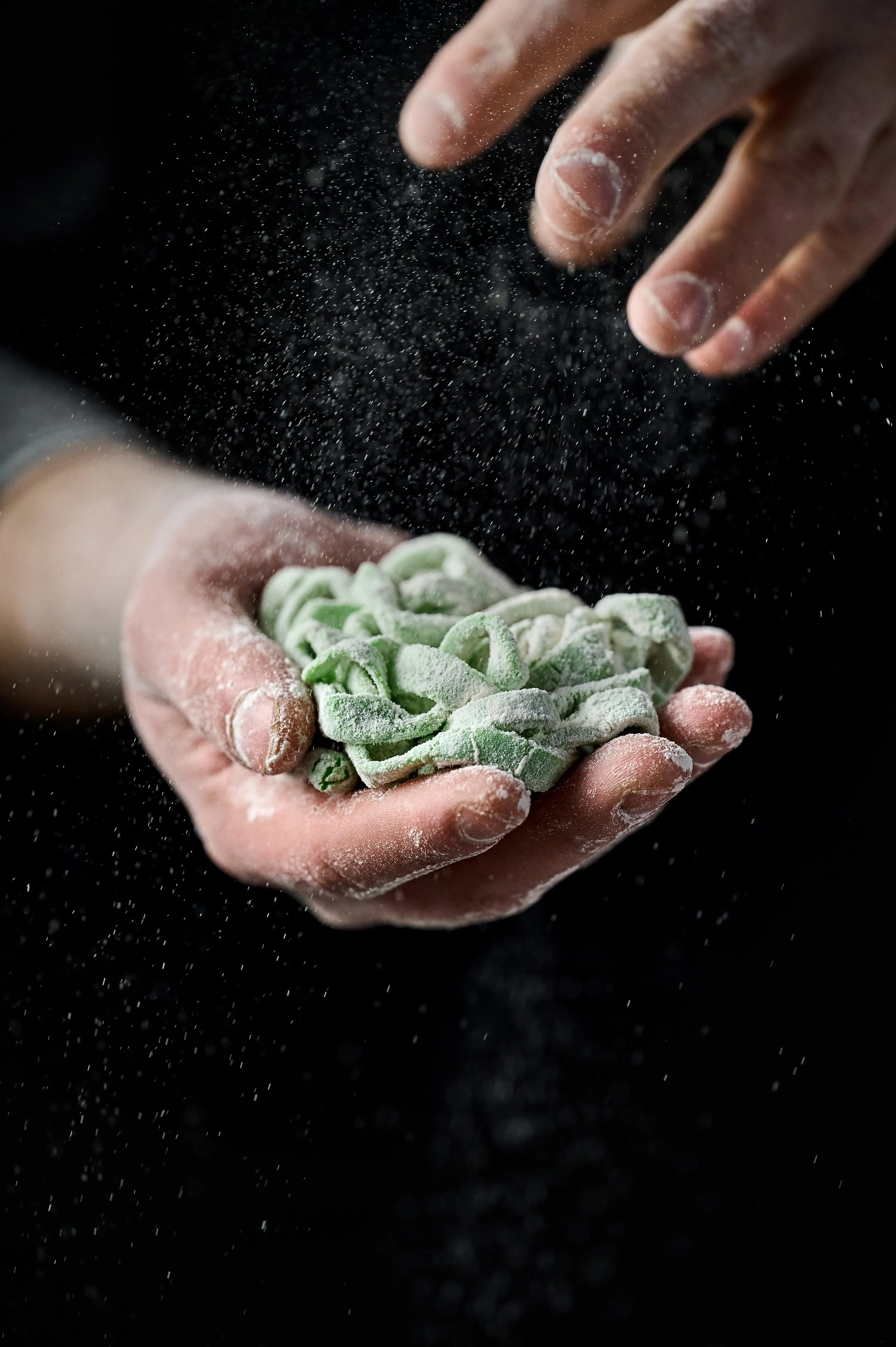 Чоловік тримає у руках домашні макарони