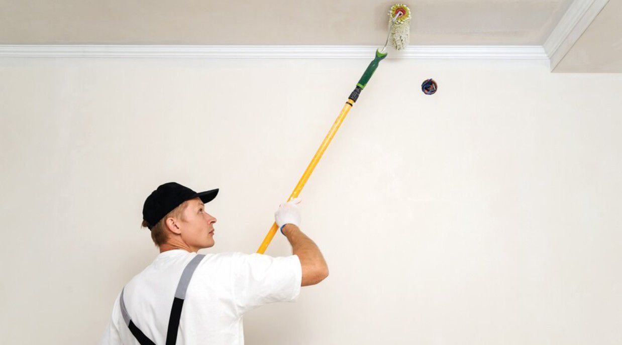Чоловік фарбує стелю
