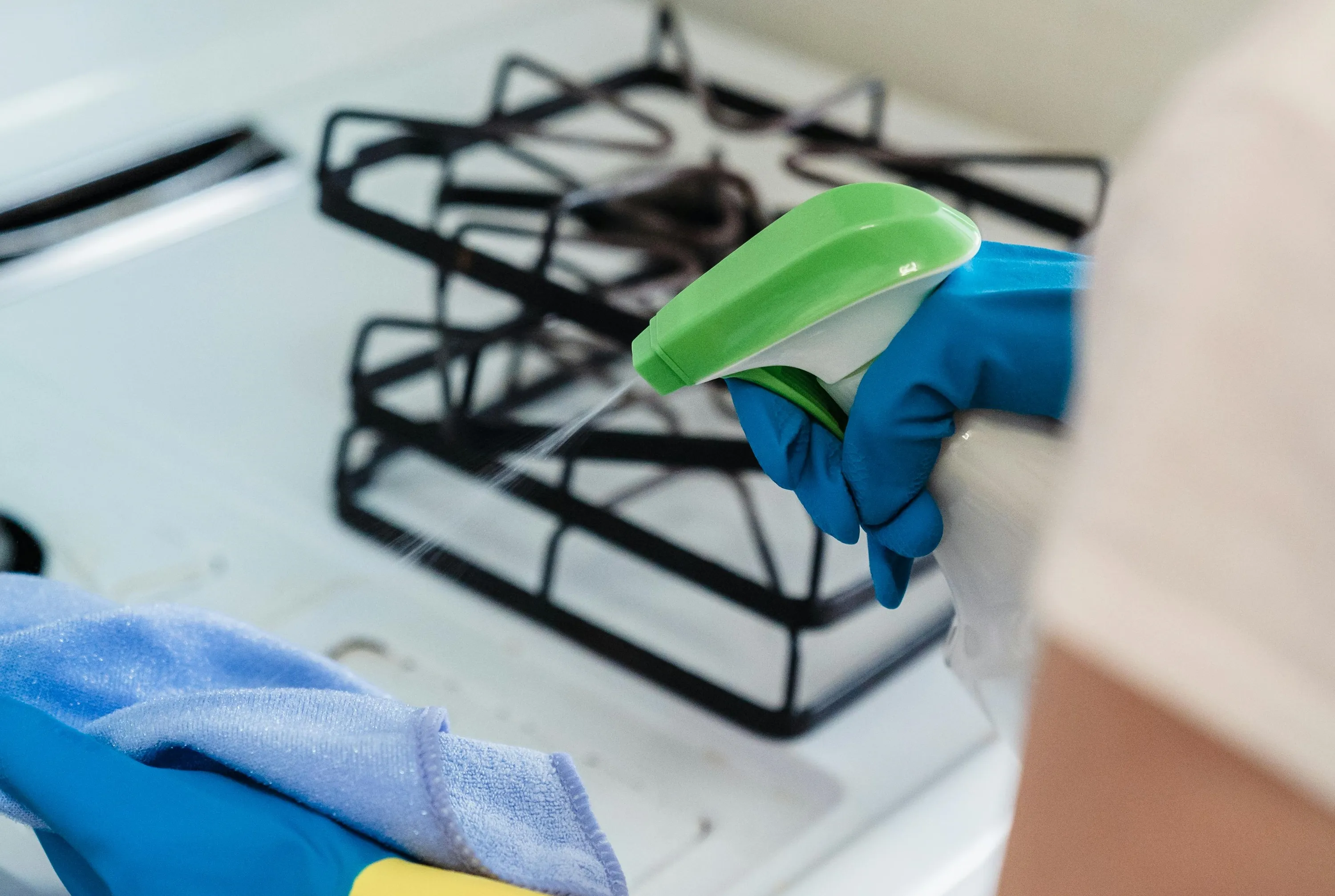 Женщина моет кухонную плиту