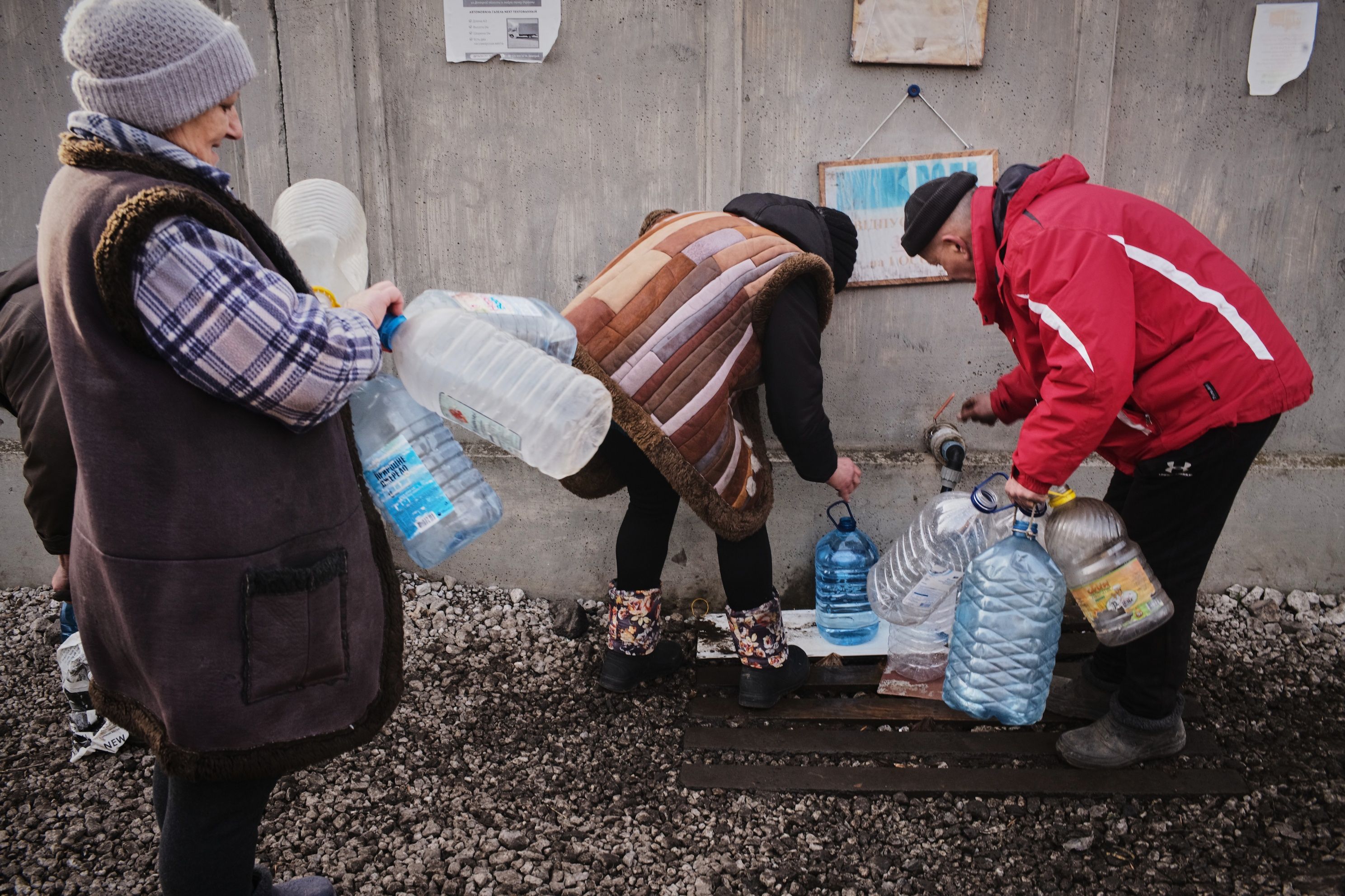 Люди наполняют бутылки питьевой водой Люди наполняют бутылки питьевой водой