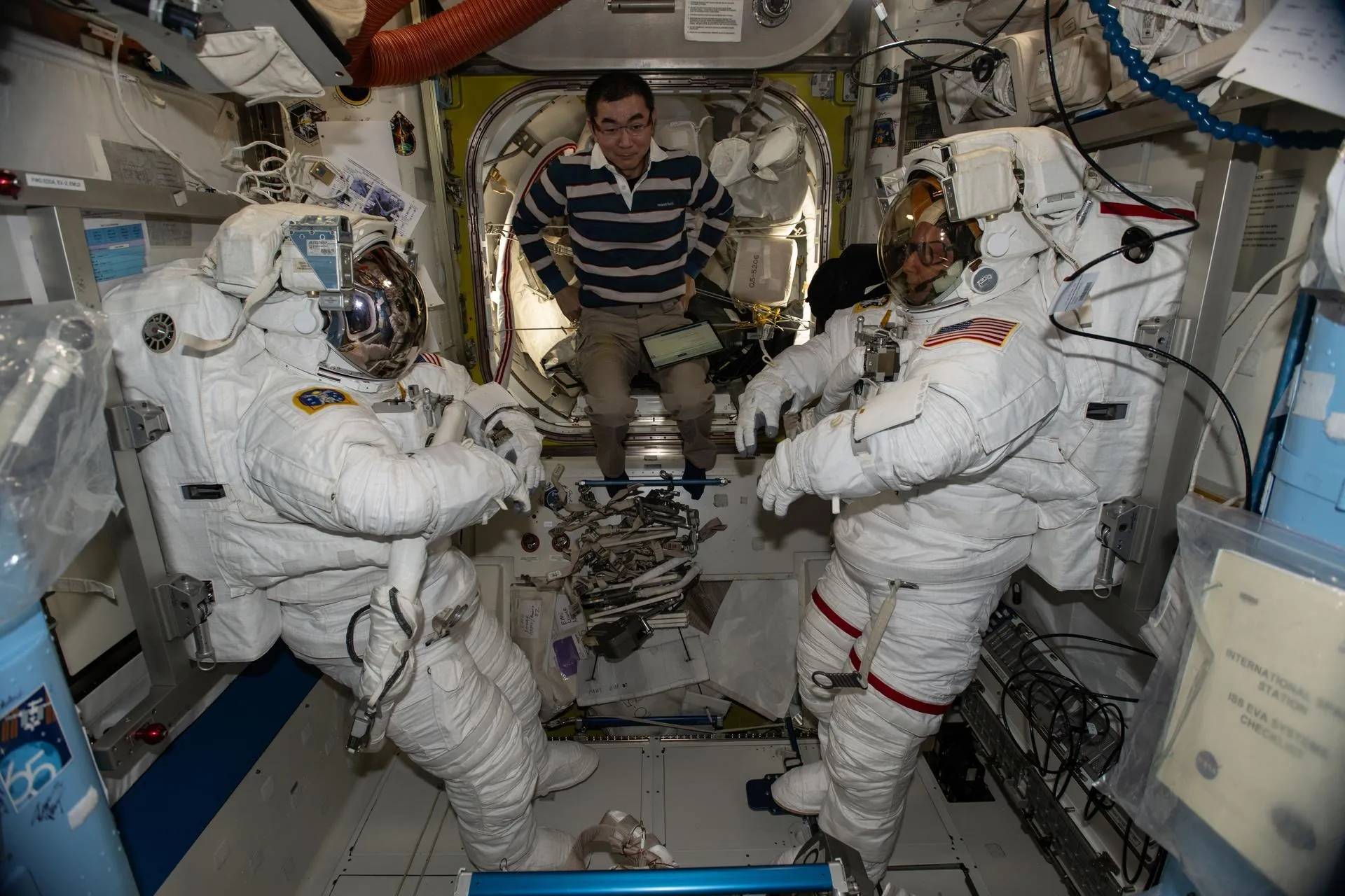 Кімія Юї допомагає астронавтам NASA Зені Кардман і Майку Фінку під час перевірки скафандрів Кімія Юї допомагає астронавтам NASA Зені Кардман і Майку Фінку під час перевірки скафандрів